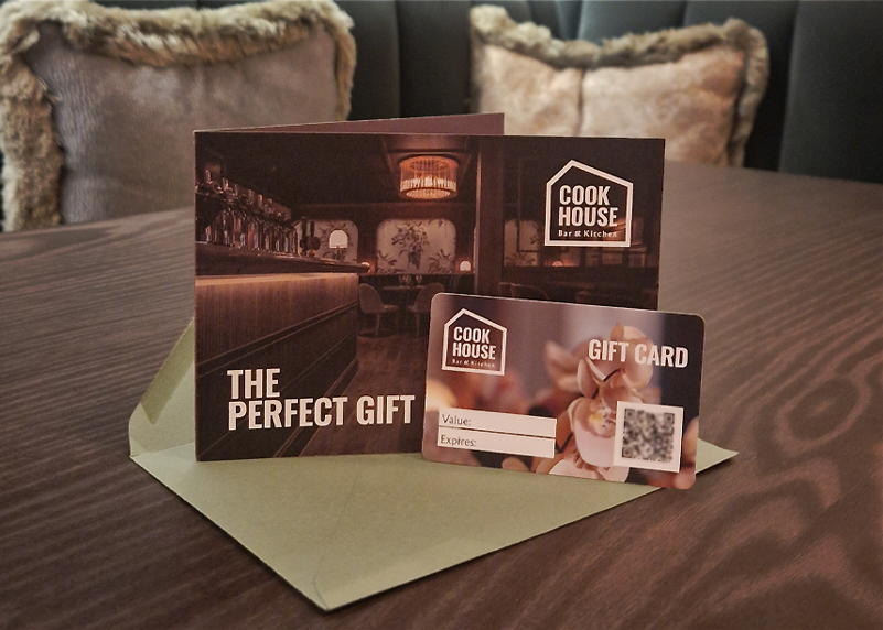 A credit card sized gift card for Cook House Bar & Kitchen is shown with a card showing a photo of the bar, the Cook House Logo and the text "The Perfect Gift", both are positioned on an olive green envelope.