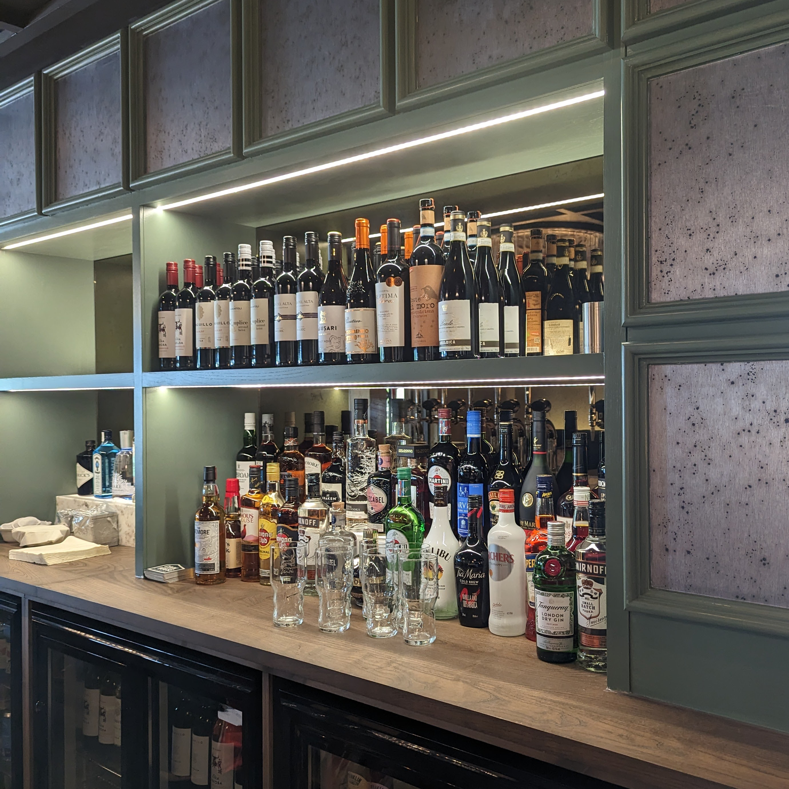A view of the shelves behind the bar of Cook House Bar & Kitchen, on the shelves are bottles of wines and spirits.
